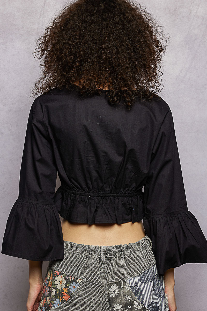 Back view of black cropped blouse with gathered peplum hem and 3/4 flared sleeves