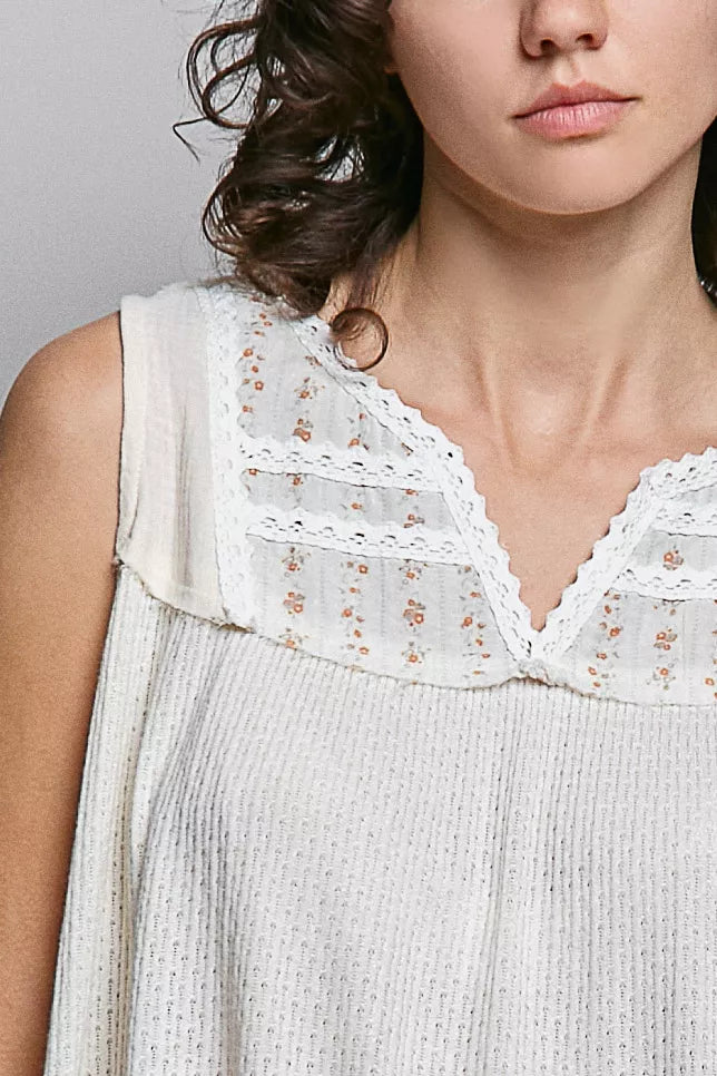 Close-up of natural V-neck lace detail with small floral embroidery on sleeveless top