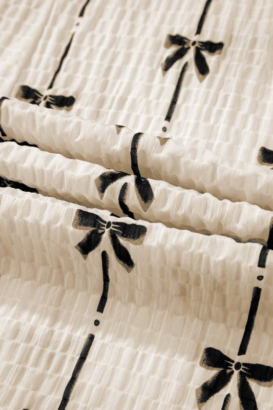 Close-up of cream fabric on bow-texture top with black bow and stripe print
