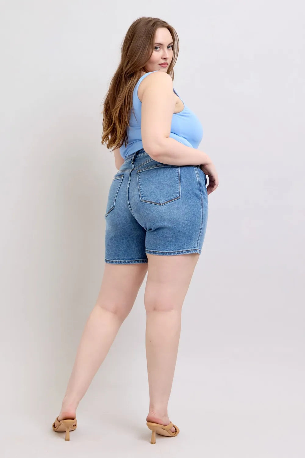 Medium wash denim shorts, three-quarter back view with stitched back pockets