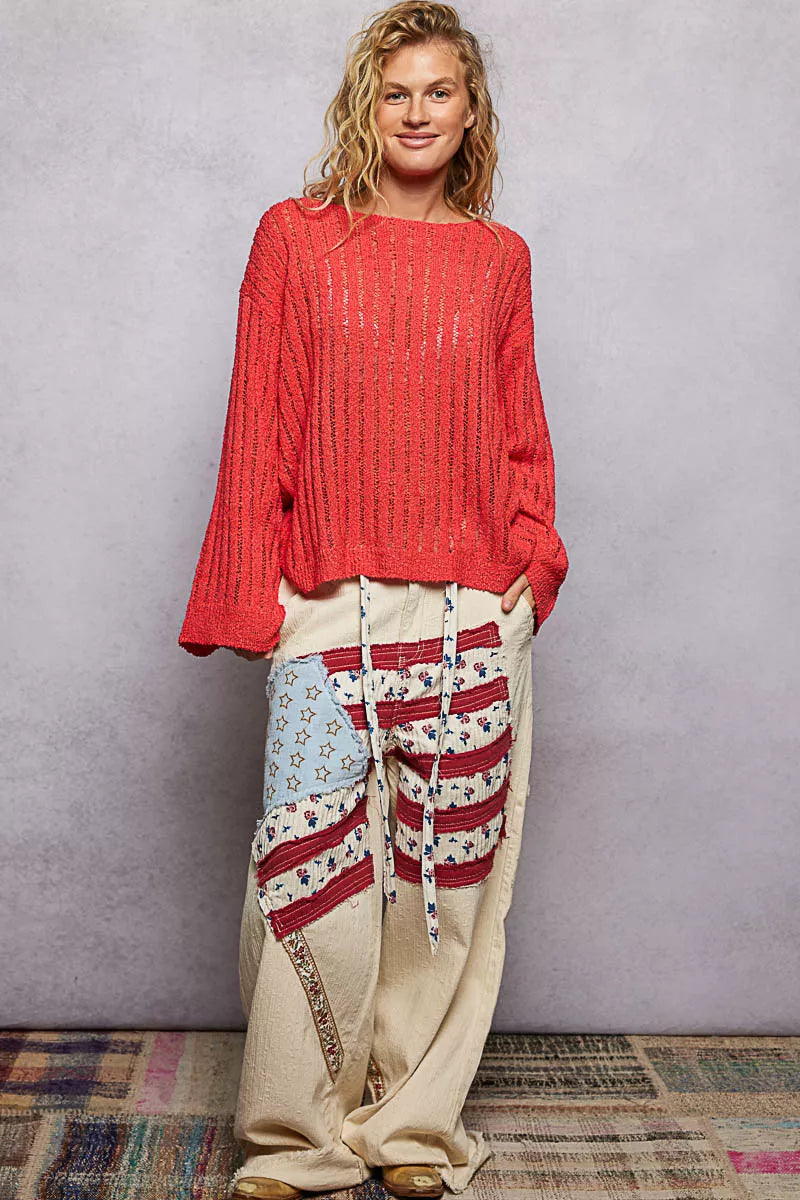 Red open-weave long-sleeve sweater worn over light pants