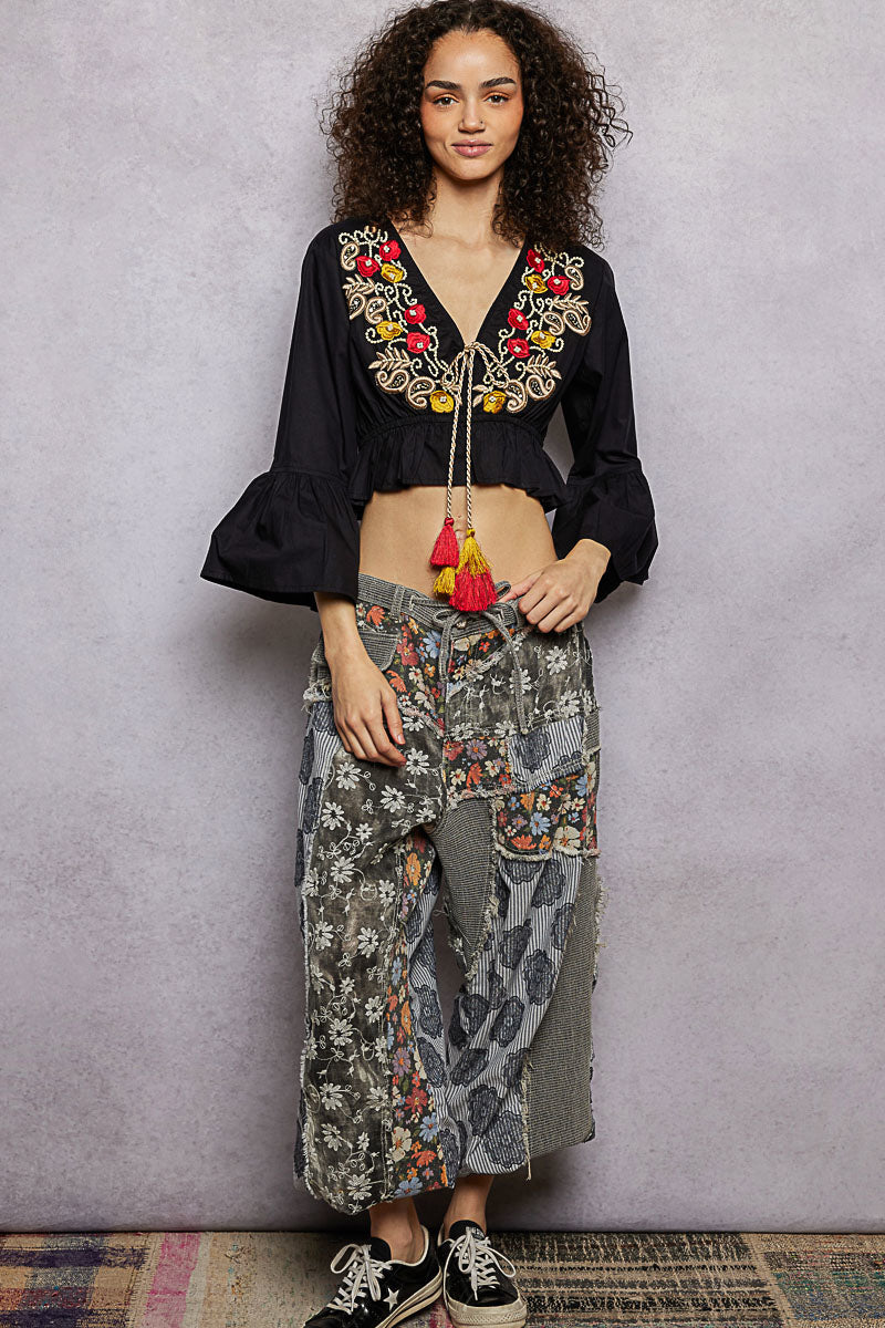 Black cropped blouse with red-and-yellow floral embroidery, V-neck, and tassel trim tie