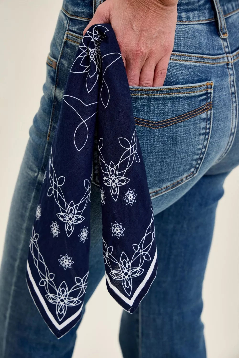 Bandana loop on medium-wash flare jeans; navy scarf with white floral pattern