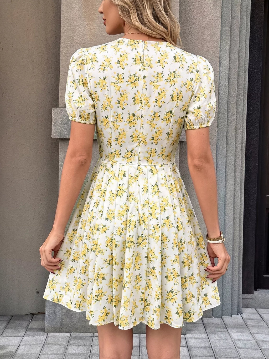 Back of yellow floral mini dress with puff sleeves and pleated skirt