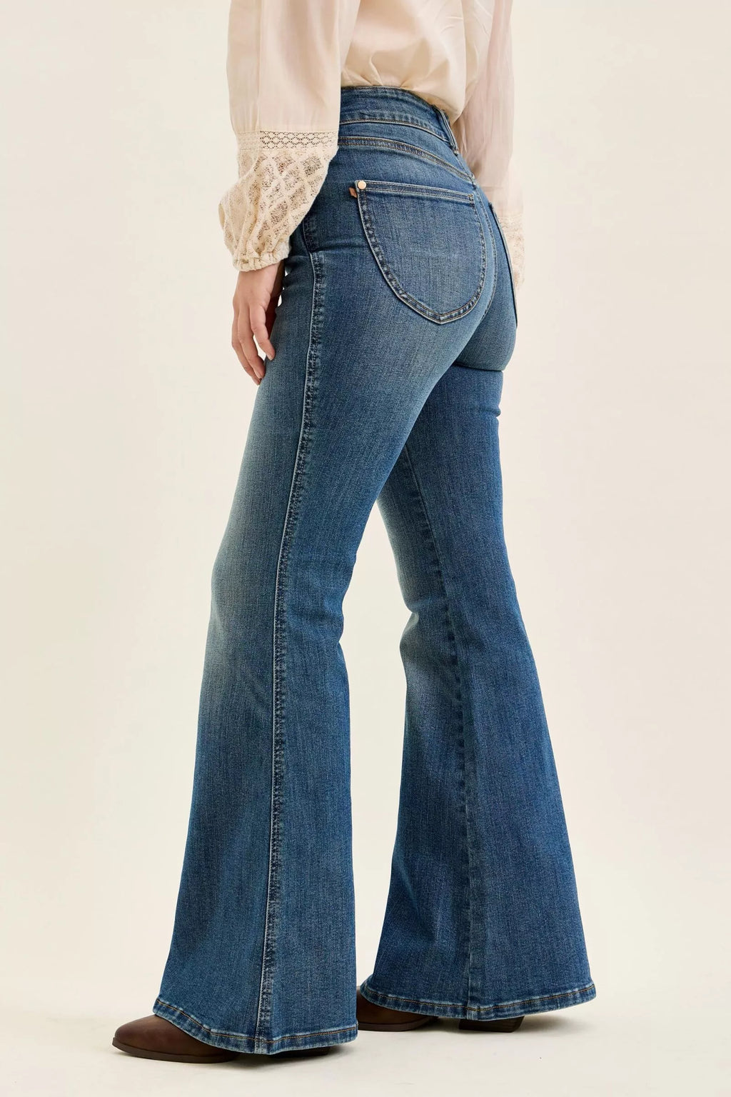 High-waist dark denim flare jeans, side view with back pocket stitching