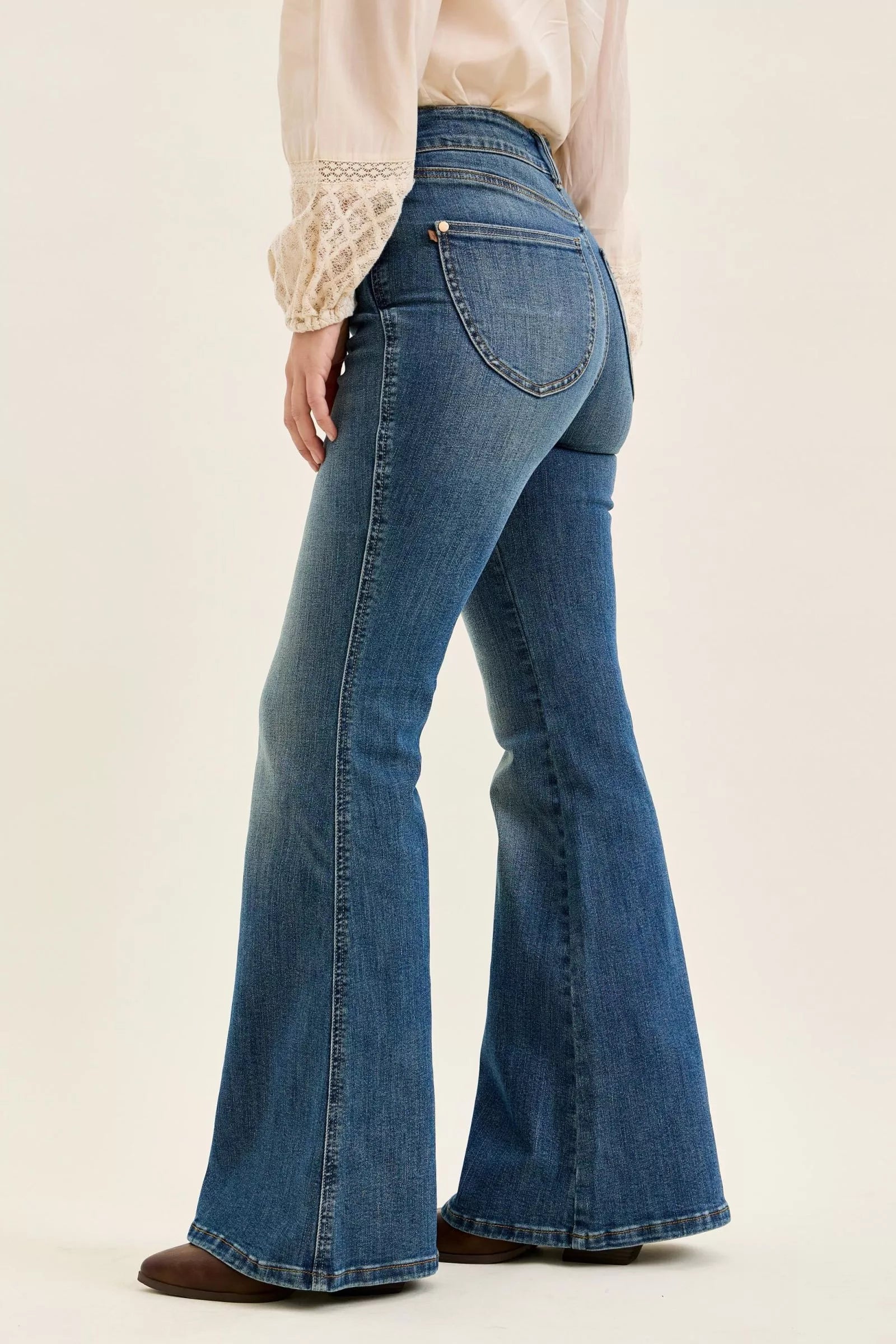 High-waist dark denim flare jeans, side view with back pocket stitching