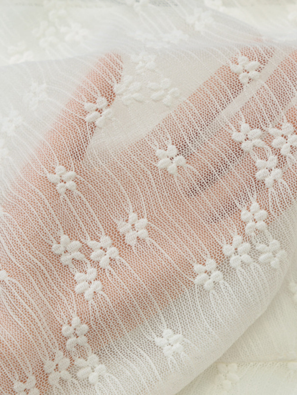 Close-up of cream lace fabric with floral embroidered pattern