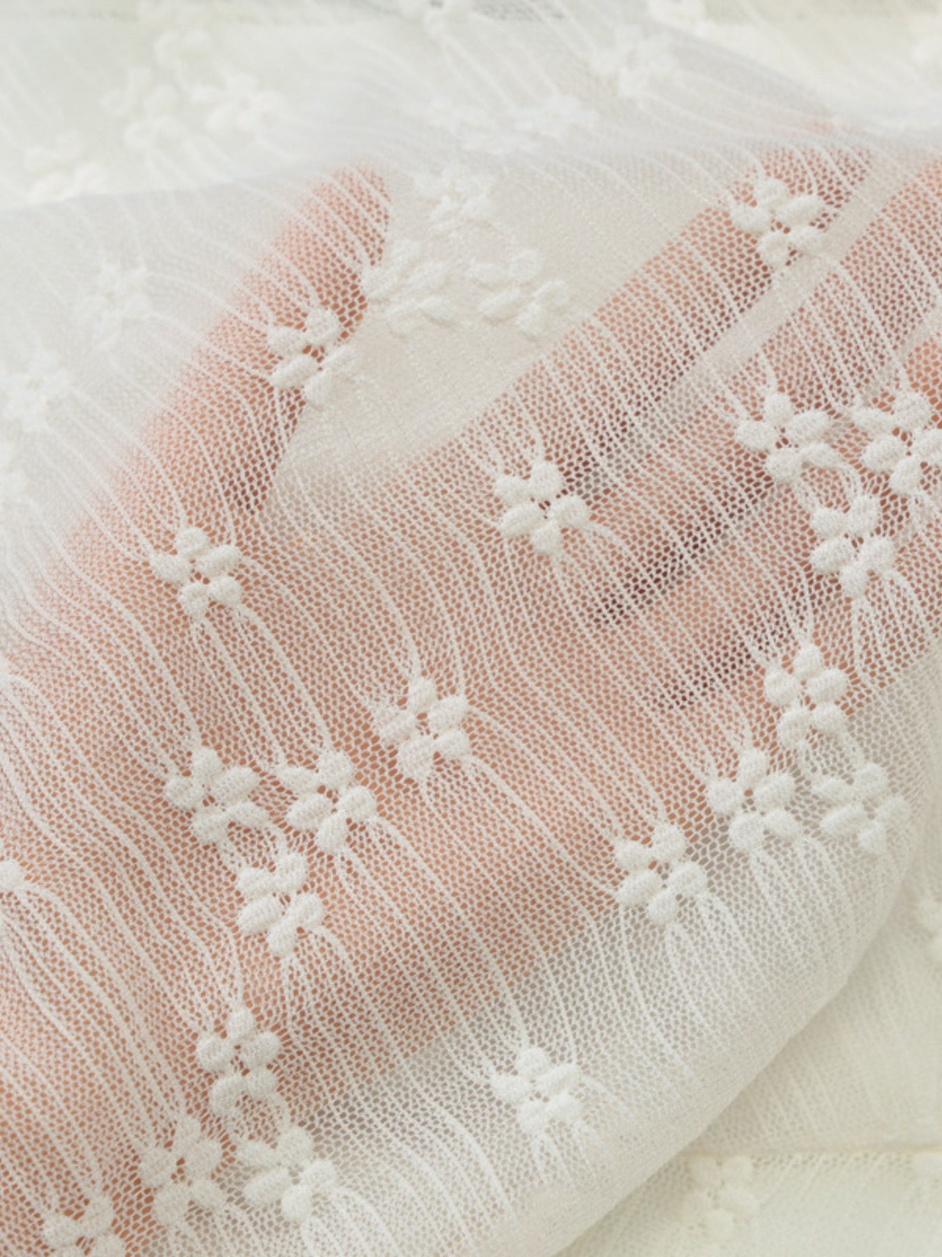 Close-up of cream lace fabric with floral embroidered pattern