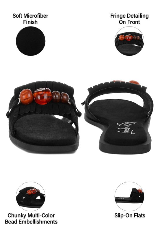 Black slip-on flat sandals with soft microfiber finish, beaded front, and fringe detailing