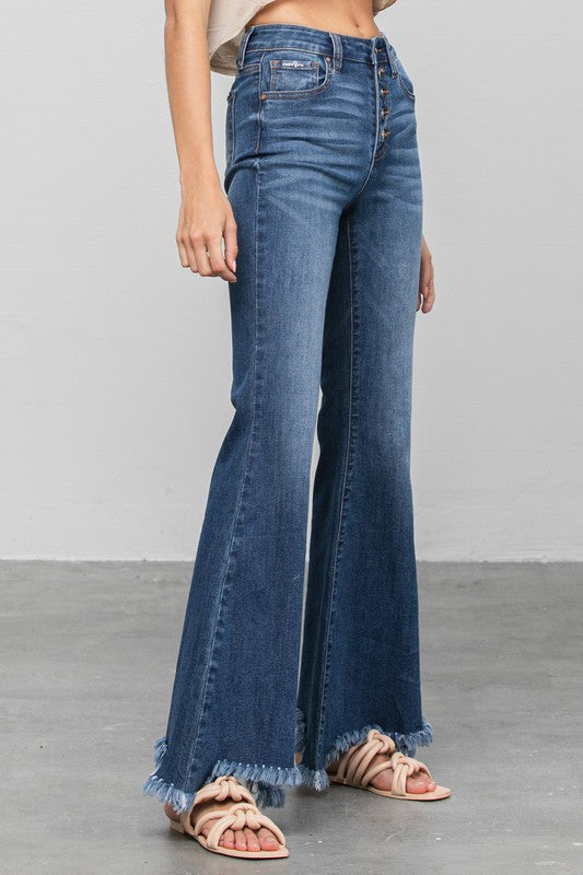 Close-up of dark blue flare jeans: front buttons, seams, and frayed hem
