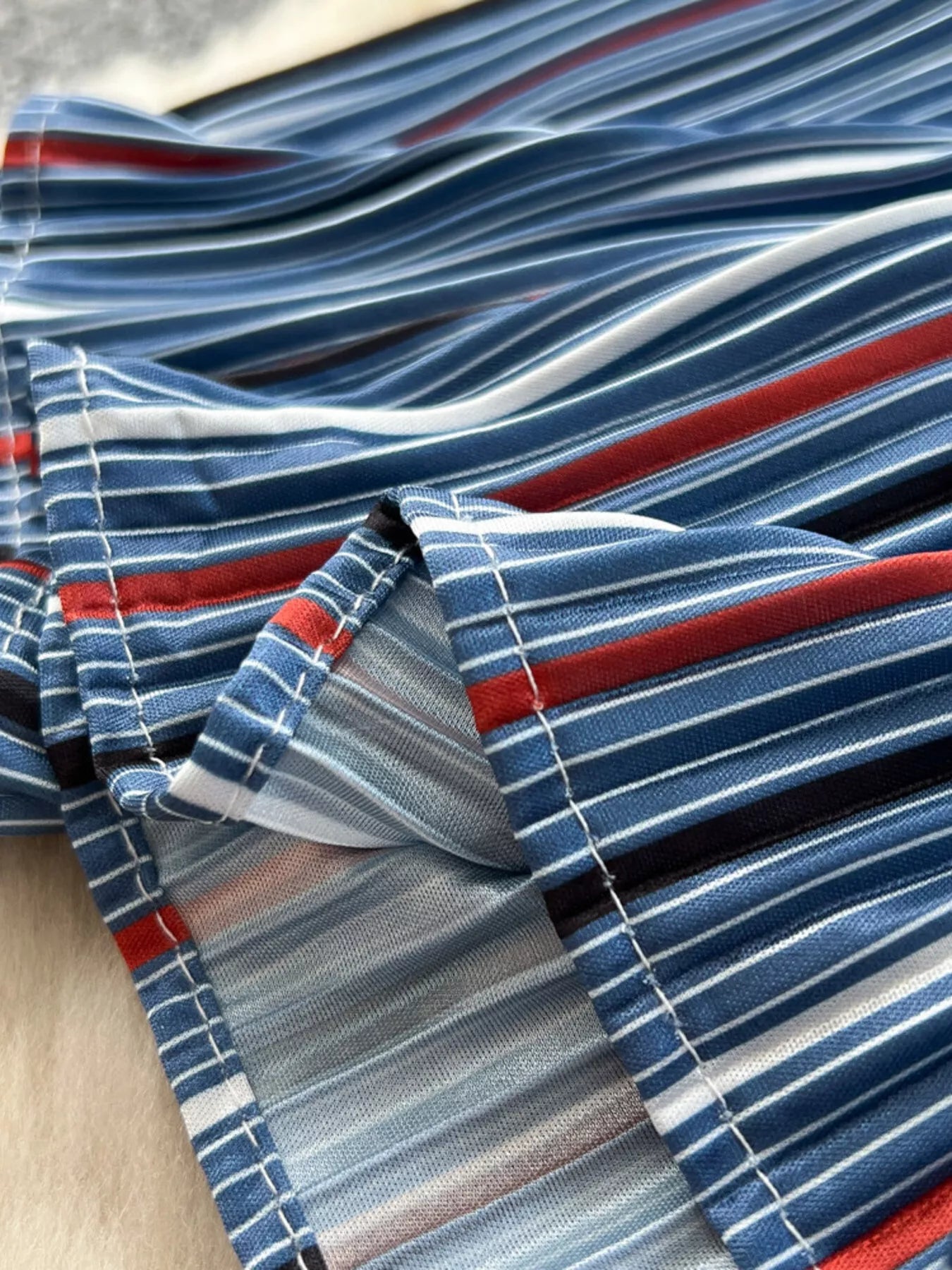 Frente del bajo: tela a rayas azul, blanca y roja en capas con costuras y frunce