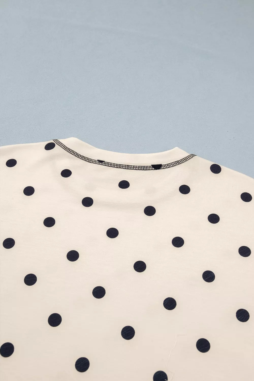 Cream short-sleeve tee with navy polka dot pattern and contrast edge trim