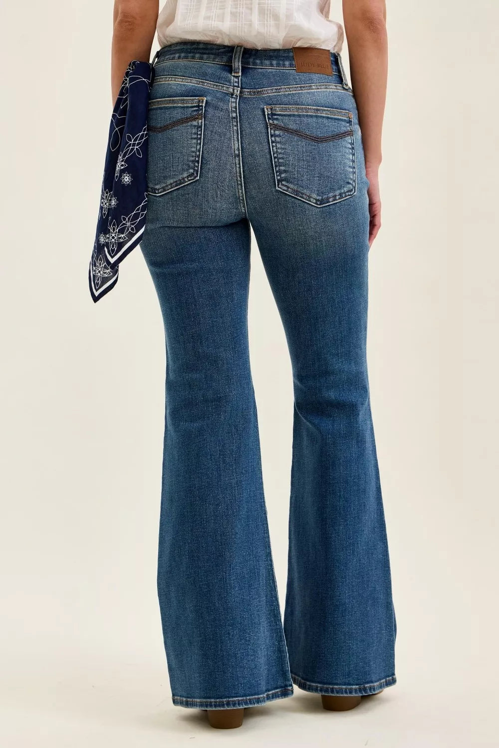 Mid-rise flare jeans in medium wash; back with patch pockets and triple-needle stitching