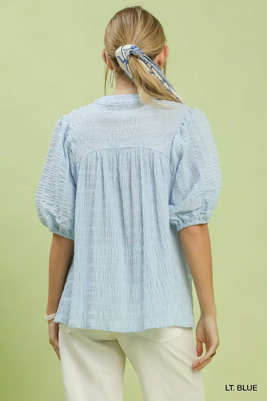 Back view of light blue textured puff-sleeve blouse with gathered yoke