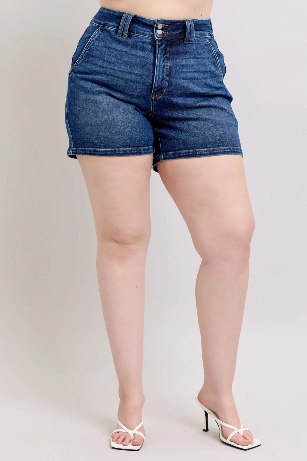 Rear three-quarter view of dark denim shorts with back yoke and pocket detail