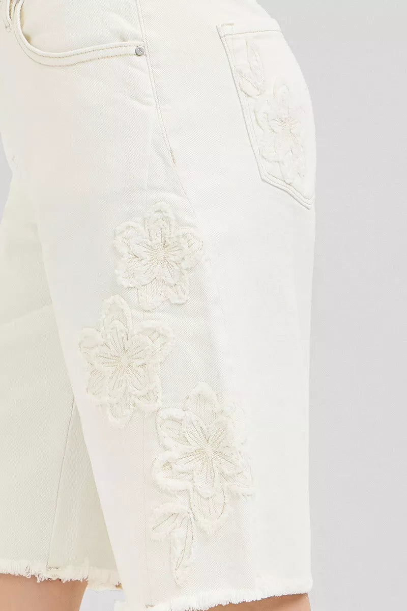 Close-up of floral embroidery on cream denim bermuda shorts