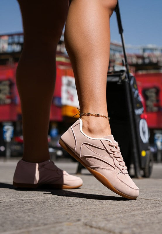 Blush-pink sneakers on foot, lace-up style with cushioned collar and gum outsole