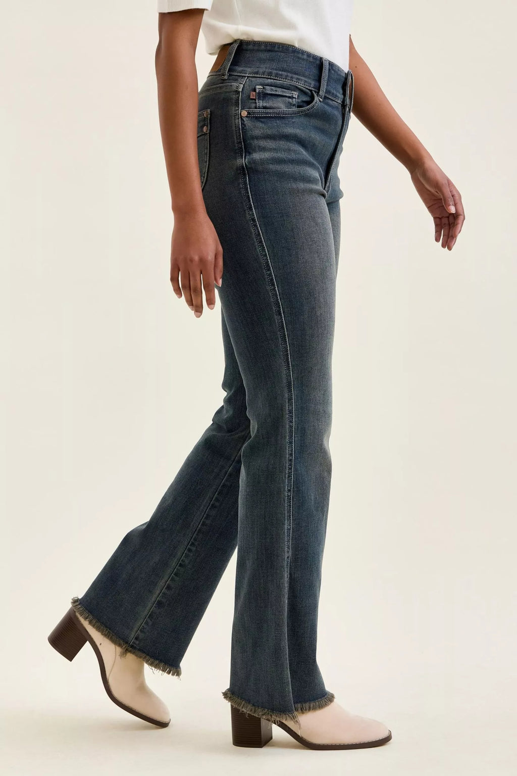 Side view of medium-wash high-waist jeans with double-button detail and frayed hem