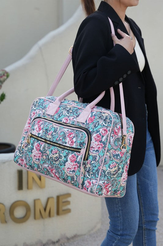 Botanical print duffle bag worn on shoulder, with front zip pocket and side strap