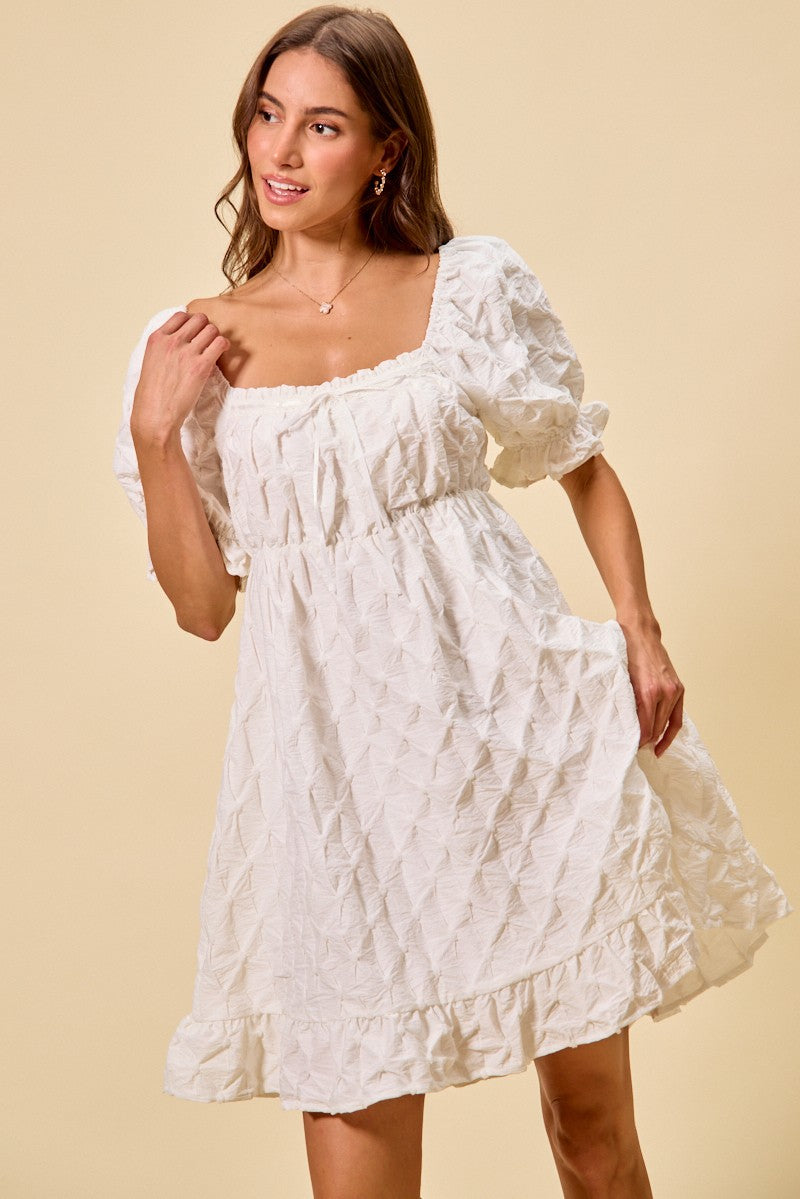 Off-white mini dress with ruched bust, puff sleeves, and textured woven surface