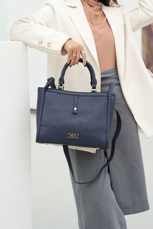MKF Melody vegan leather tote in navy, held by model with top handles and crossbody strap