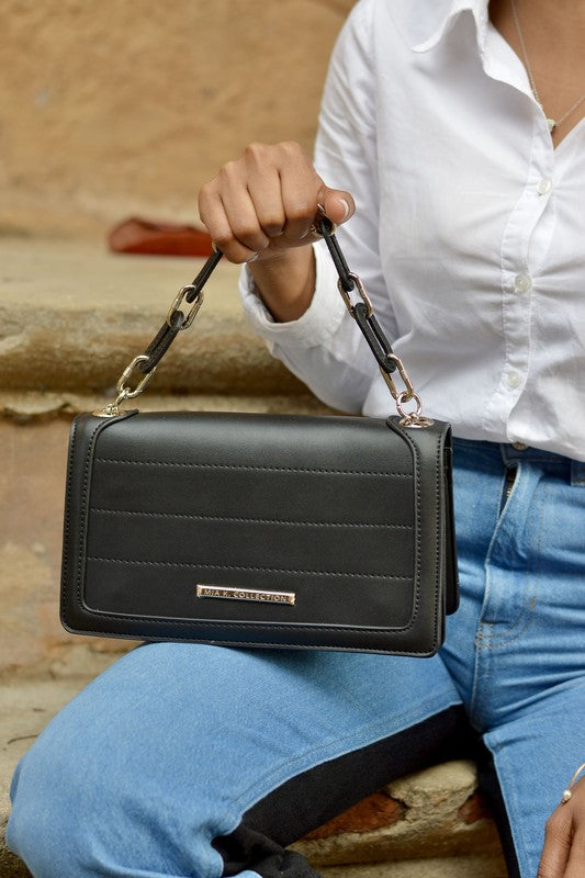 Dora crossbody bag en piel negra con correa de cadena plateada y solapa frontal