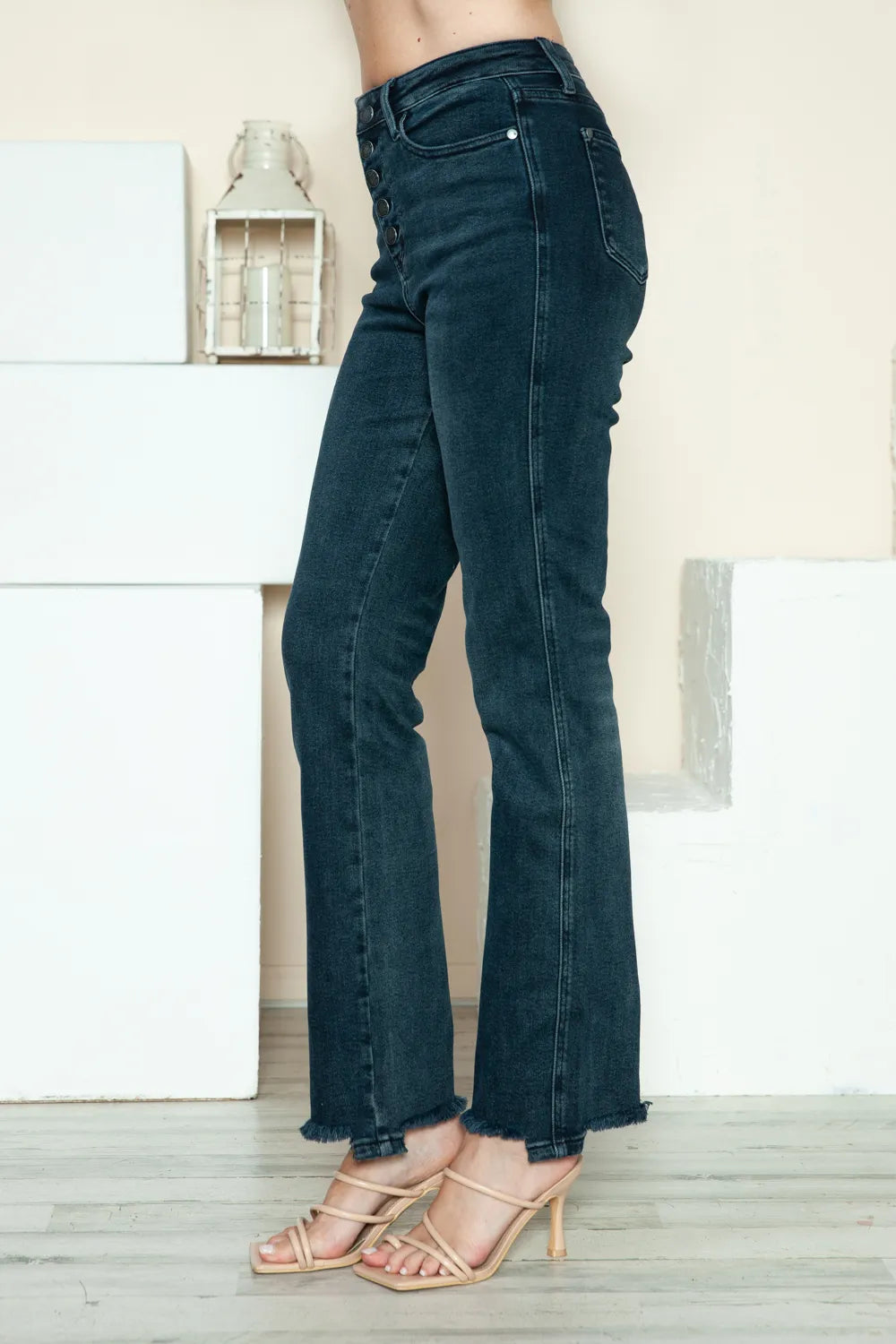 Dark blue straight jeans shown from the side; raw hem and button-fly waistband