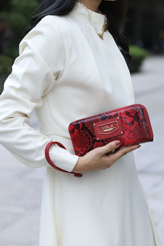 Wine snake-print travel wallet held in hand with gold logo plaque