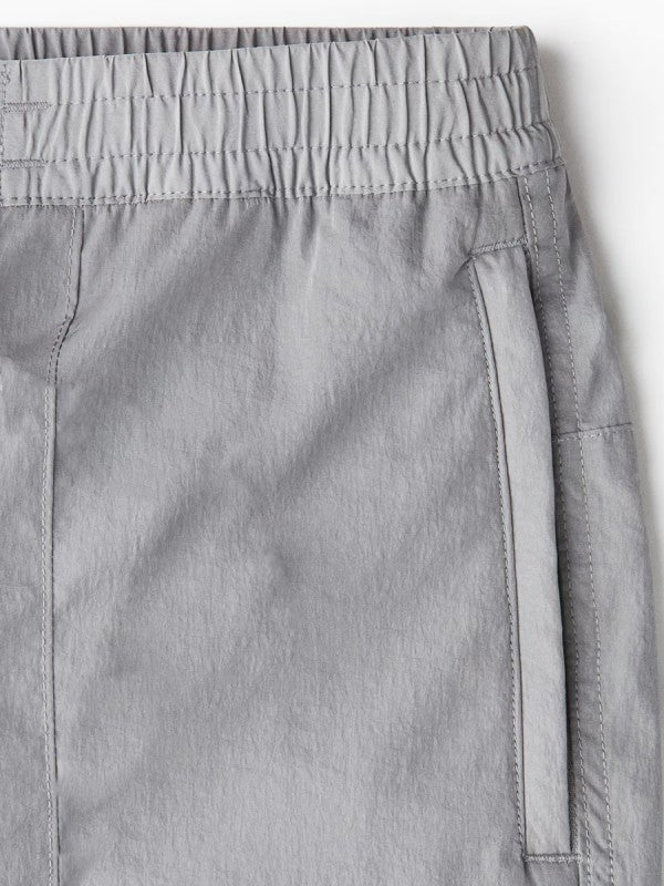 Light grey ripstop fabric cargo pants close-up with elastic waistband and side pocket
