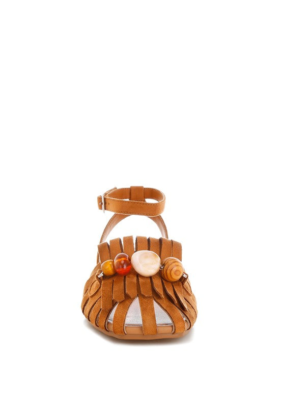 Tan cutwork flat sandals viewed from back with ankle strap and bead fringe detail