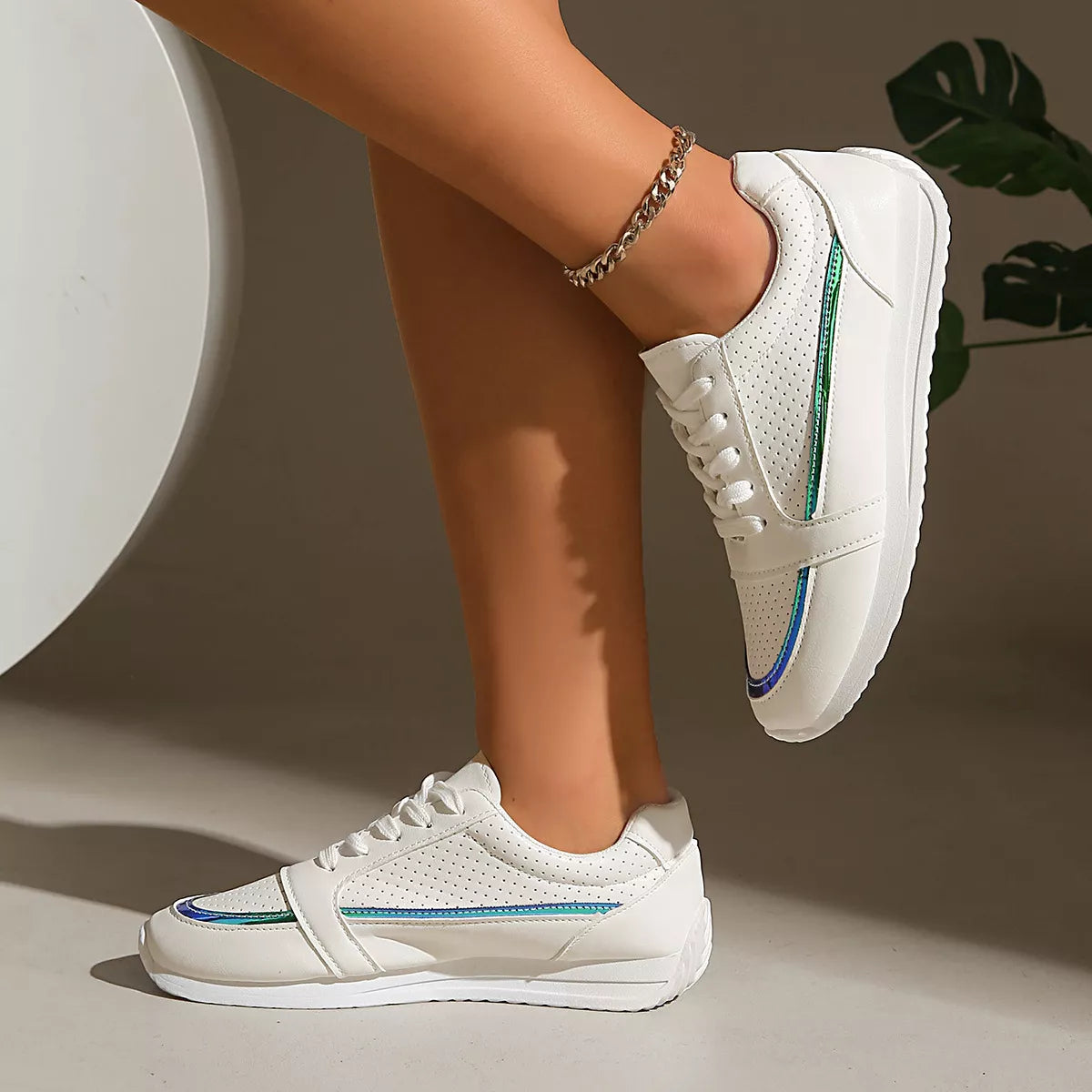 Weiße Low-Top-Sneaker, Seitenansicht mit grün-blauer Ziernaht und Schnürung
