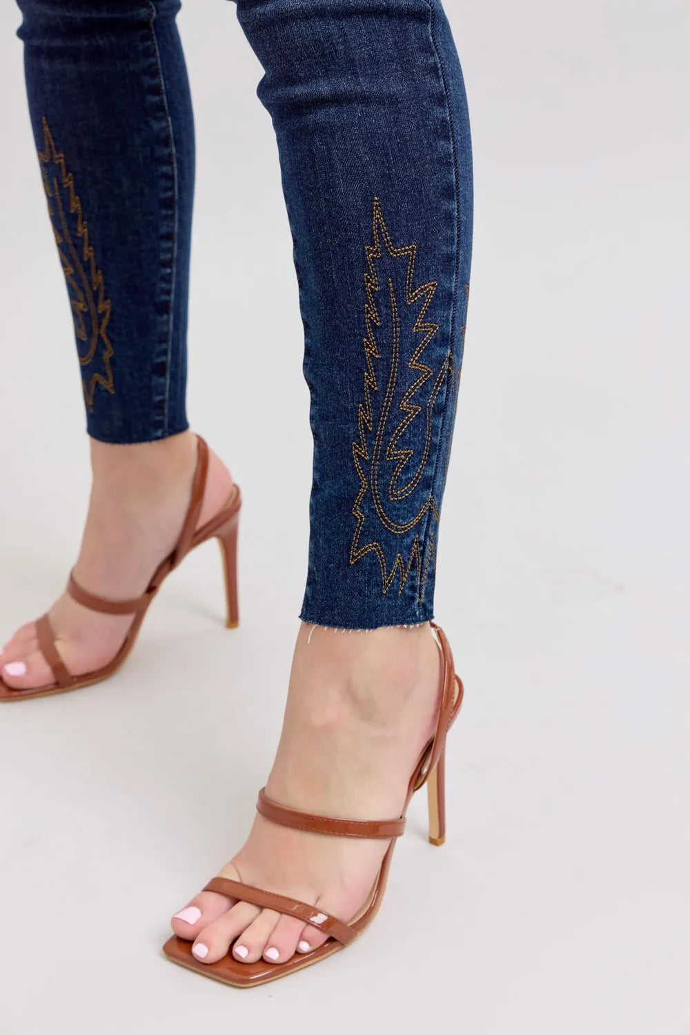 Dark blue skinny jeans close-up: embroidered calf panel along the hem