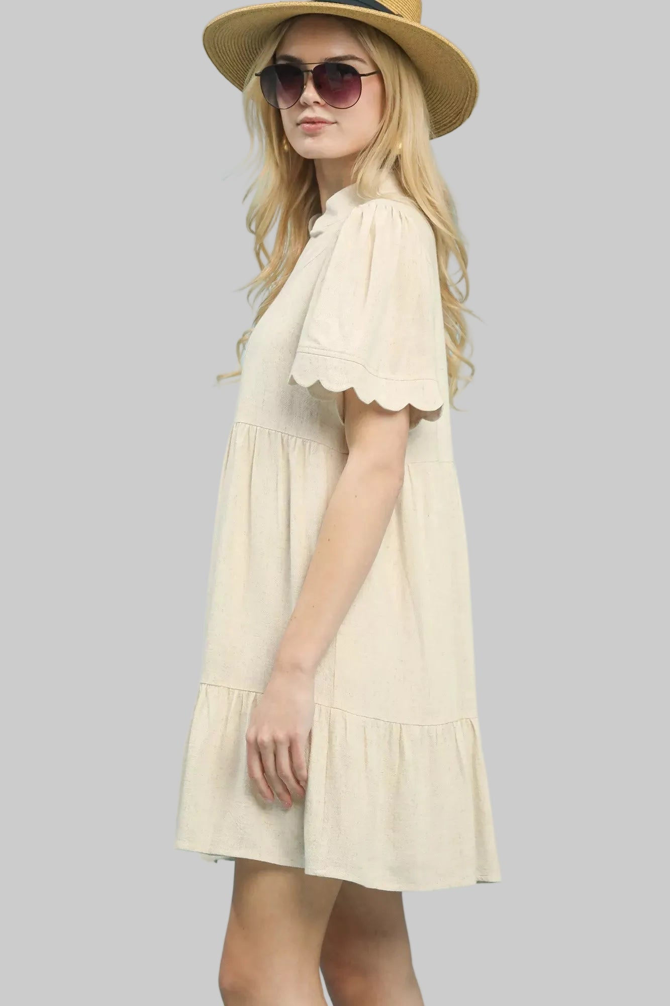 Side view: oatmeal linen babydoll dress with tiered skirt and scalloped sleeve trim