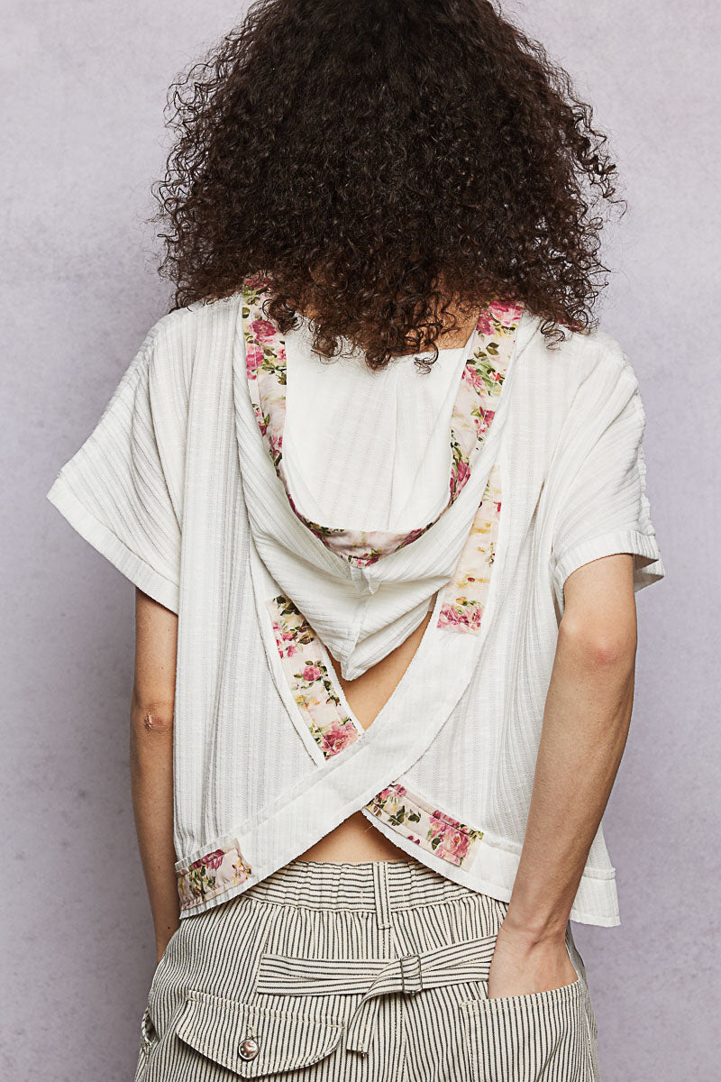Back-open hooded top in off-white with floral trim crisscross detail