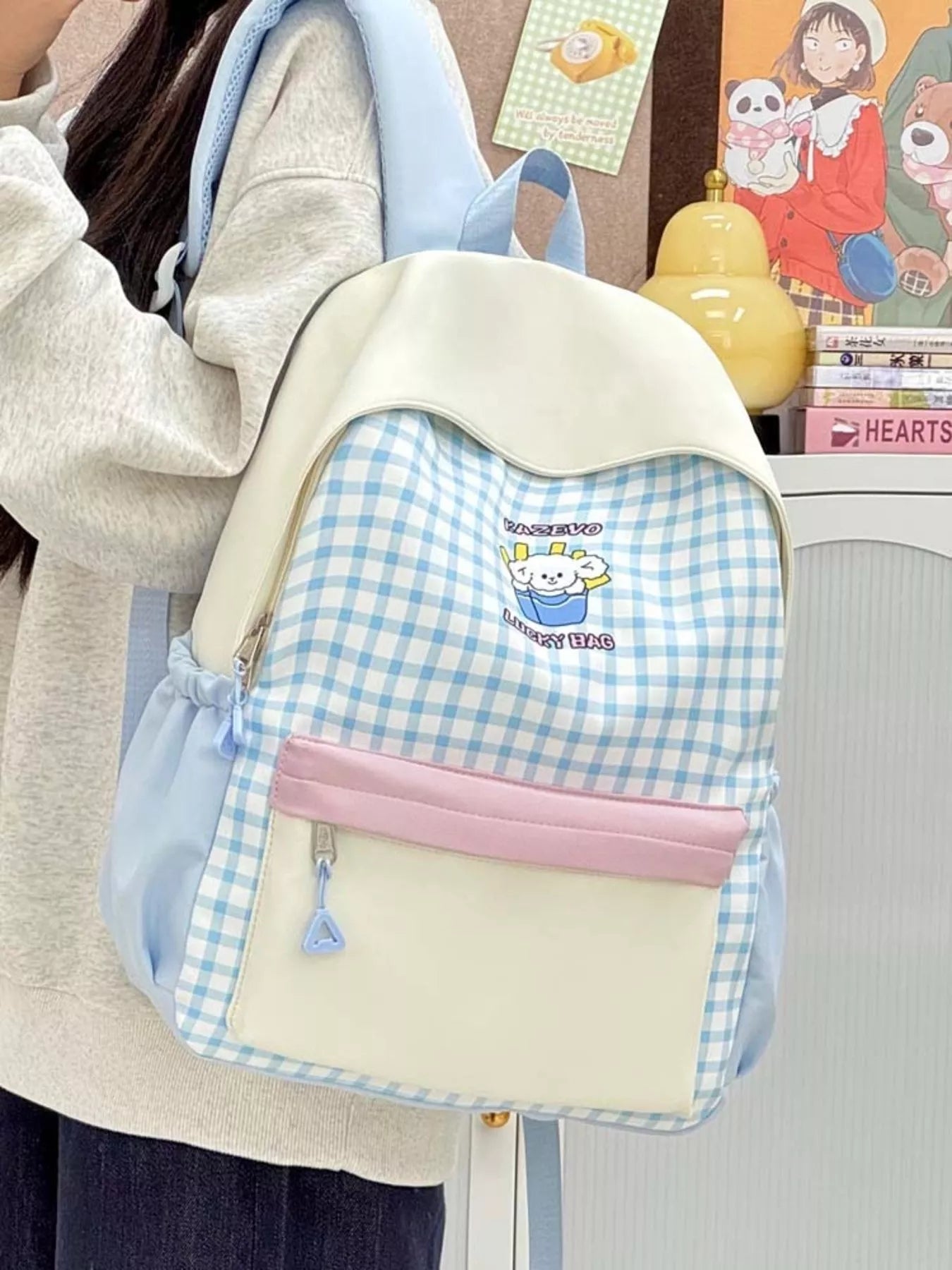 Blue gingham cartoon backpack with white flap, front pocket and triangle pull zipper.