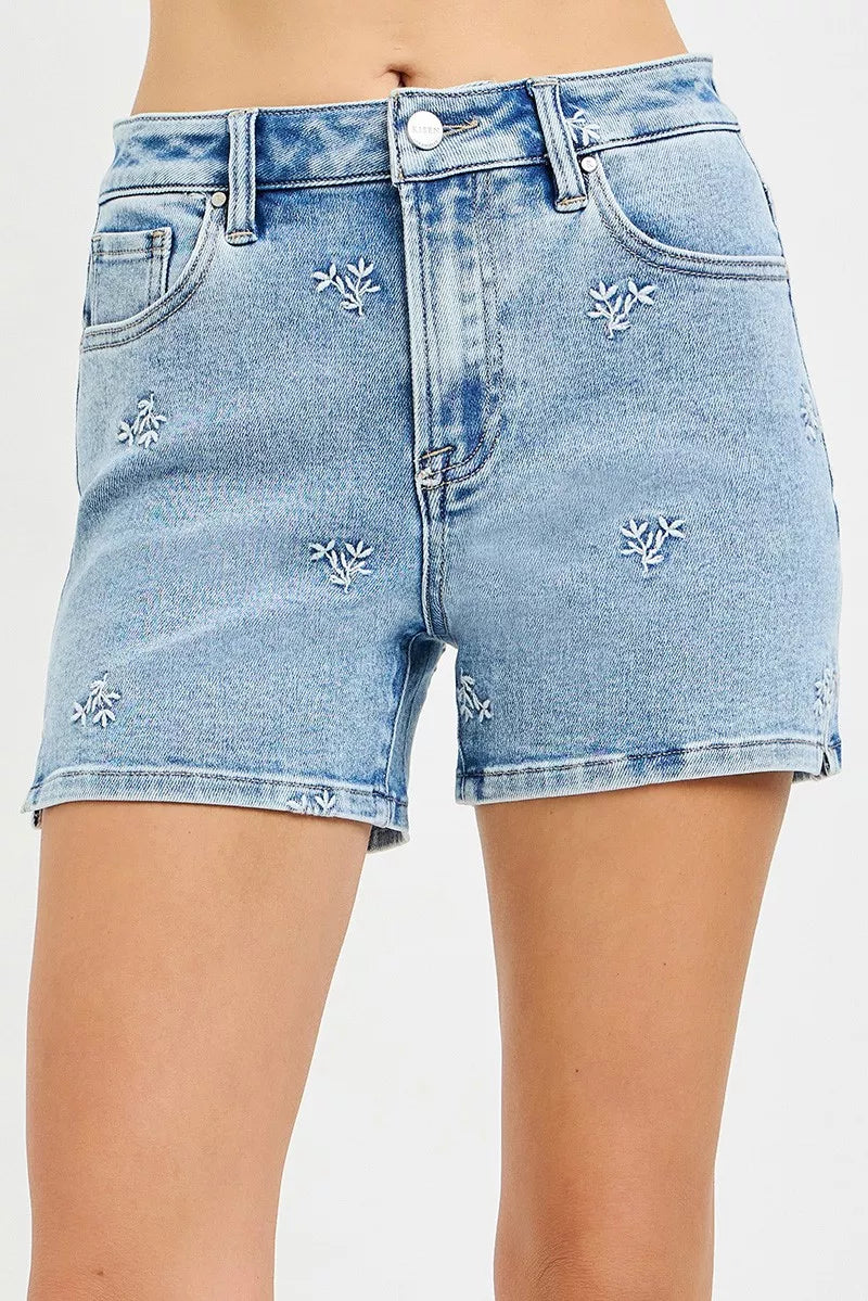 Light wash high-rise denim shorts with embroidered floral details and button front
