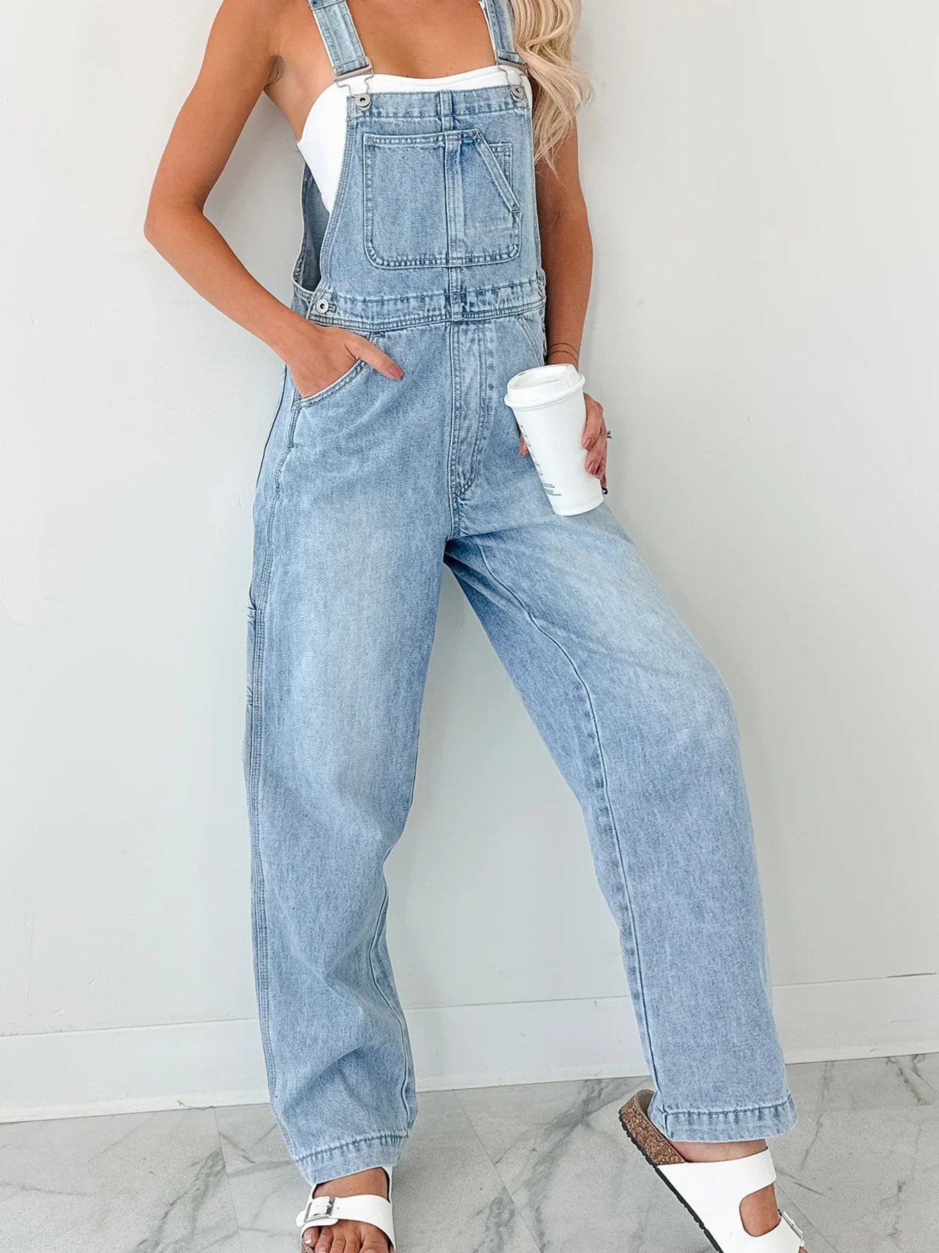 Light blue denim overalls with wide straps, relaxed straight legs and side pockets