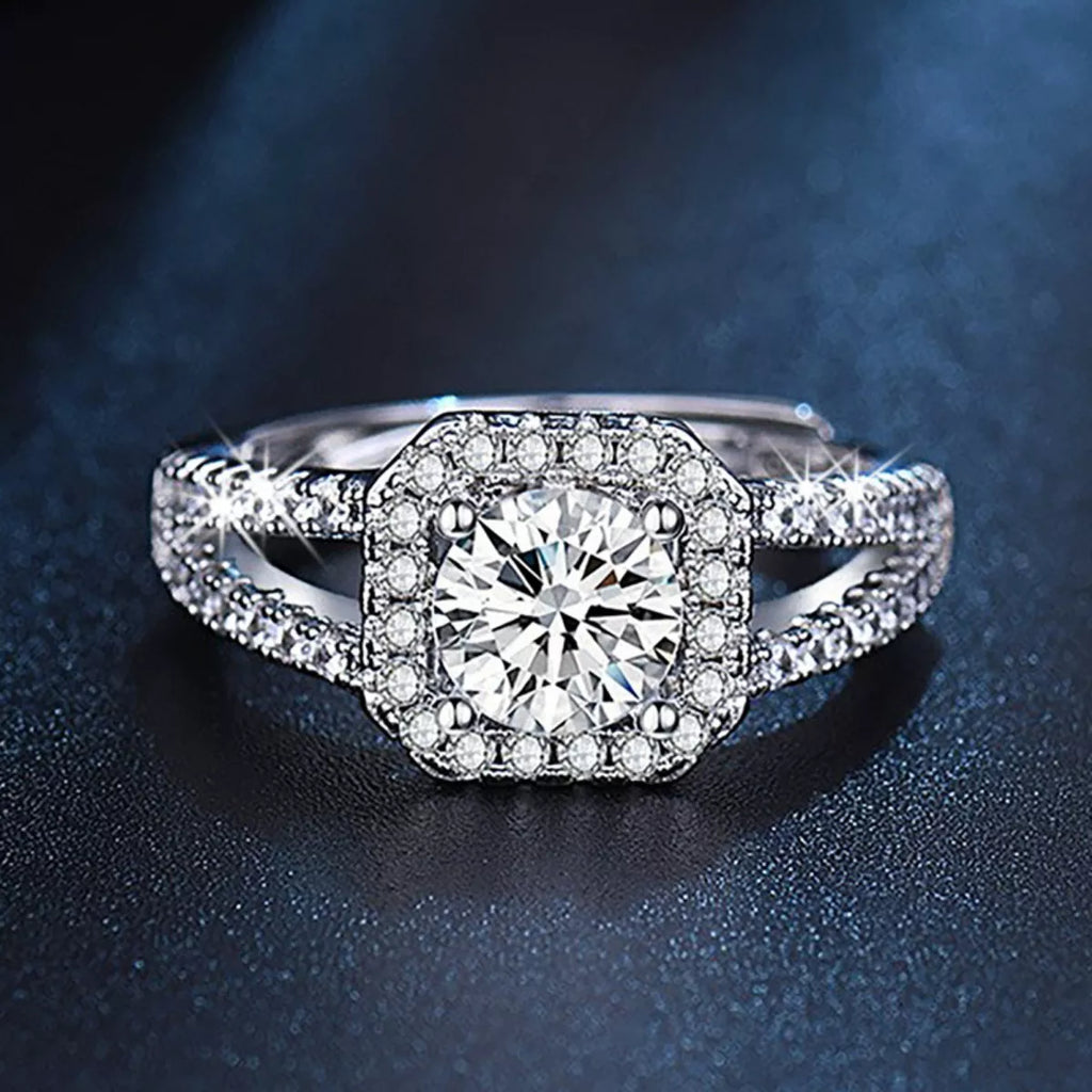 Round moissanite centerpiece surrounded by halo stones on a silver pavé band ring
