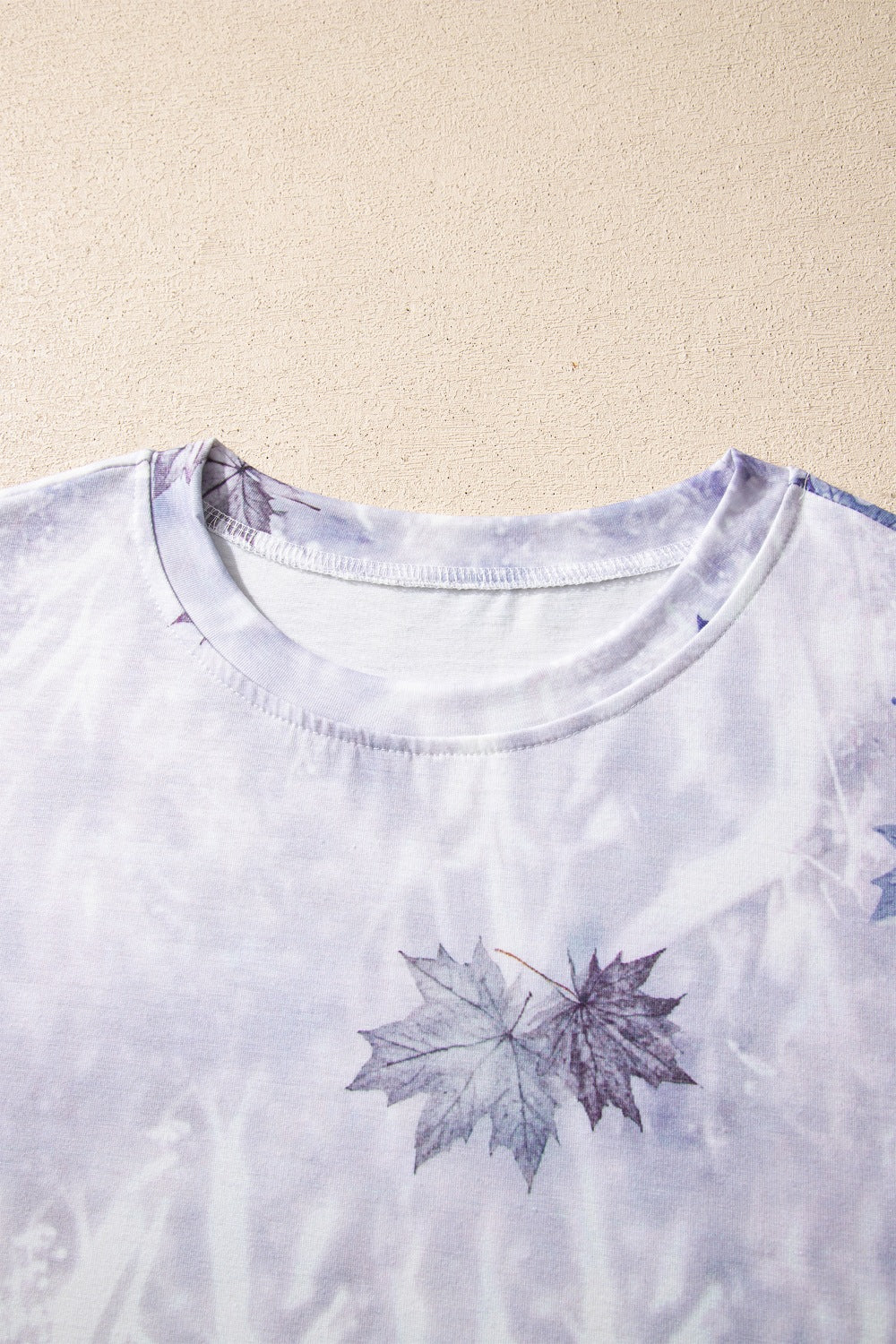 Crew neck of light gray tunic tee with purple and blue woodland leaf camouflage print