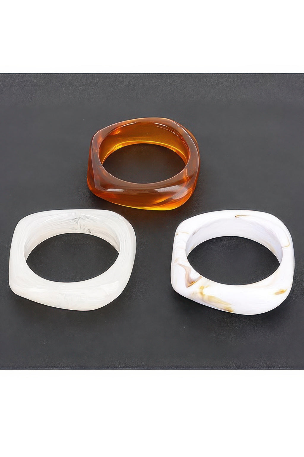 Three resin bangles: amber, translucent white, white with gold marbling