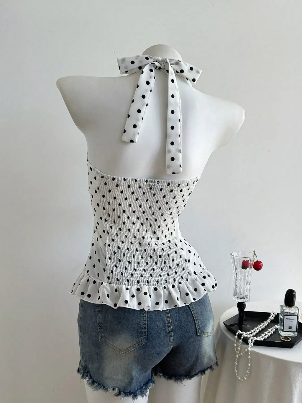 Polka dot halter neck cami back view with tied bow and ruffled peplum hem