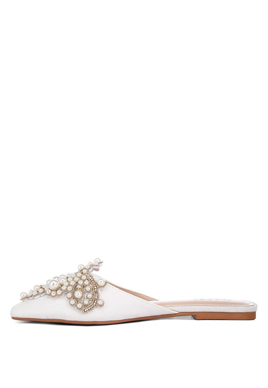 White slip-on mules with pearl bow-like detail on the upper