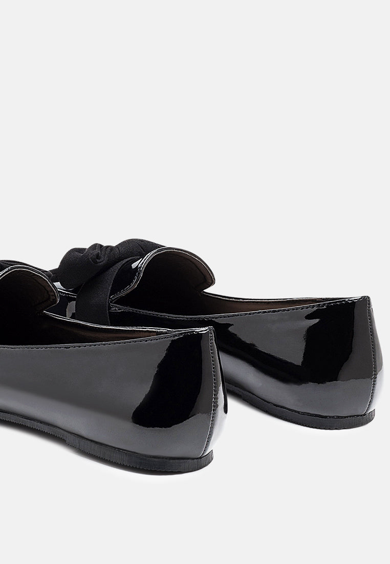 Black loafer side view: glossy upper with tied bow and low profile