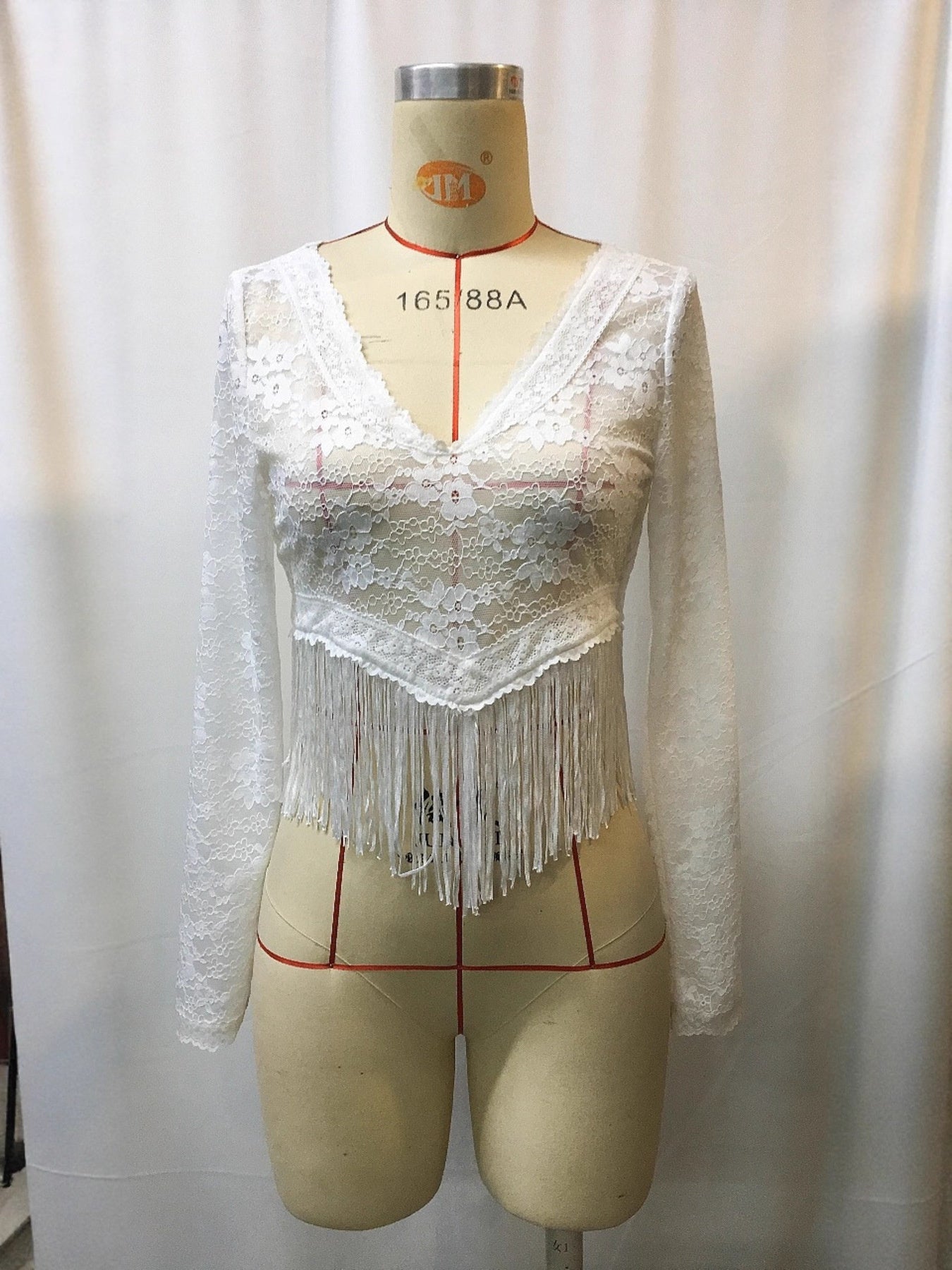 White lace long-sleeve V-neck plus size top on mannequin with fringe hem