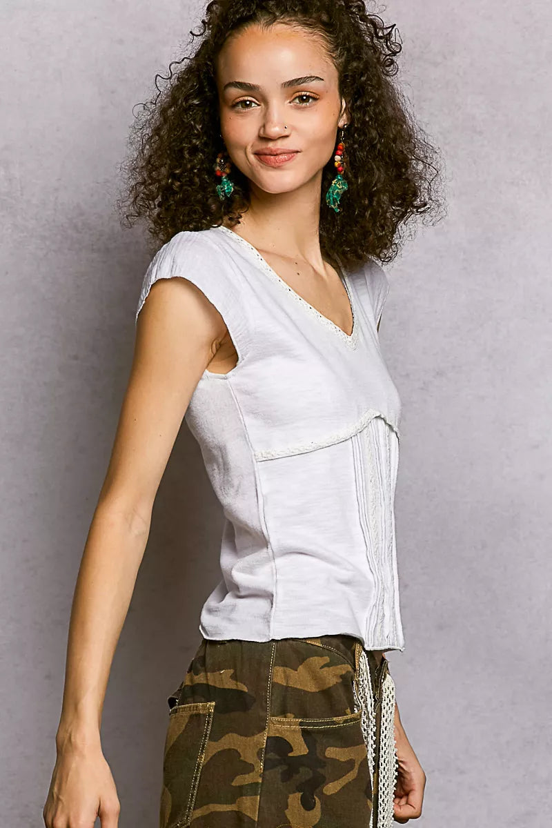 Off-white V-neck textured knit top with lace trim, angled front view