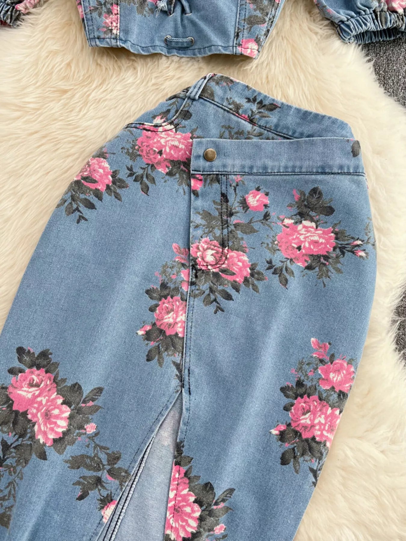 Blue denim skirt close-up: pink floral print with front seam and gold button
