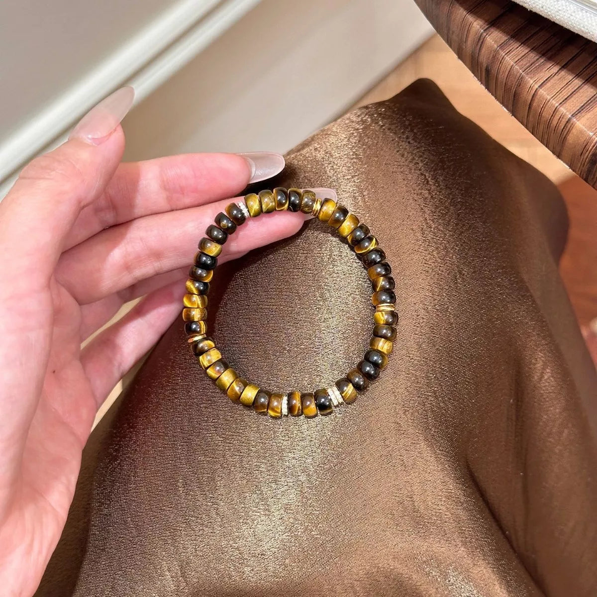 Tiger's Eye beaded bracelet held in hand, round brown and black tiger-eye beads