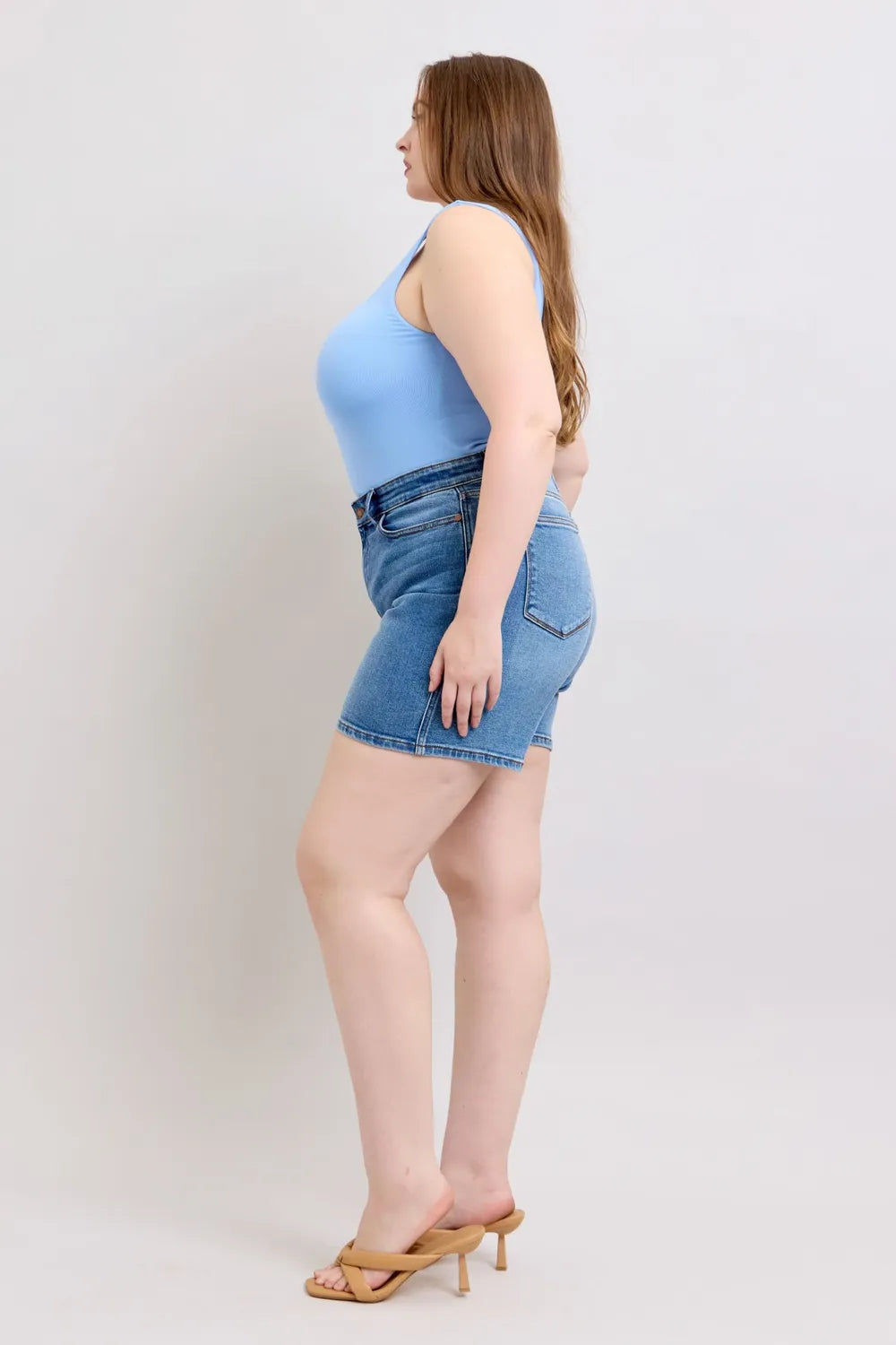 Medium wash denim shorts, side profile with front pockets and 2-button closure