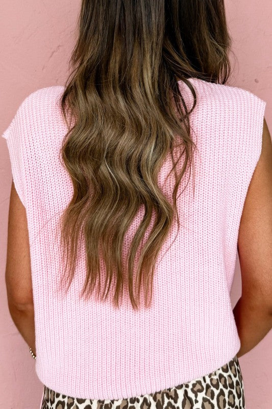 Back view of pink knit sweater vest with V-neck and button detail, sleeveless