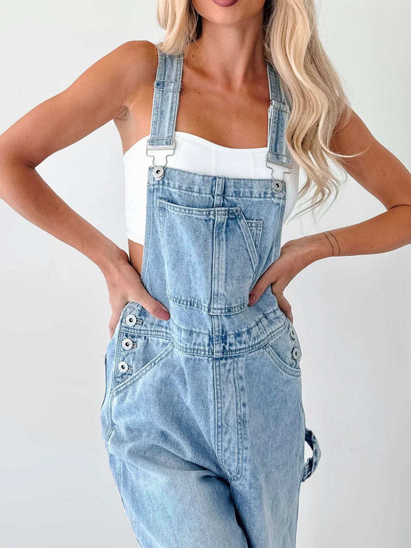 Light blue denim overalls with wide straps, front bib pocket and metal buttons